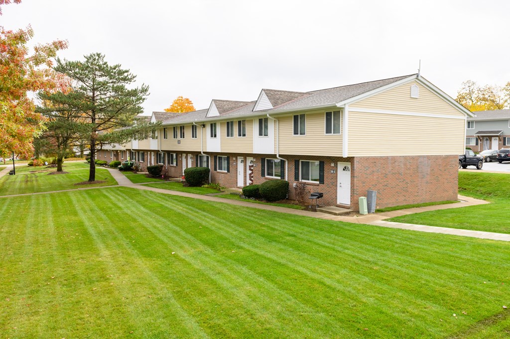 a row of houses with a green lawn and a sidewalk