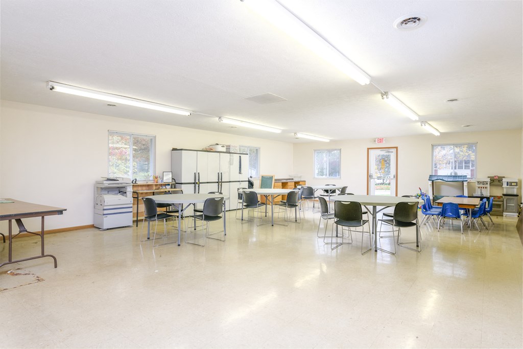 a dining room with tables and chairs and a kitchen in the back