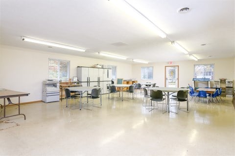 a dining room with tables and chairs and a kitchen in the back