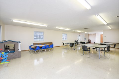 a multipurpose room with tables and chairs and a television