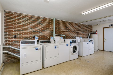 a laundry room with four washing machines and a brick wall