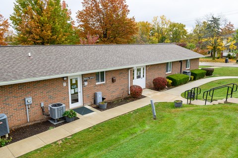 the front of a brick house with a lawn and a porch