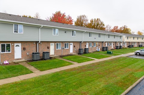 a row of townhomes with a lawn and grass