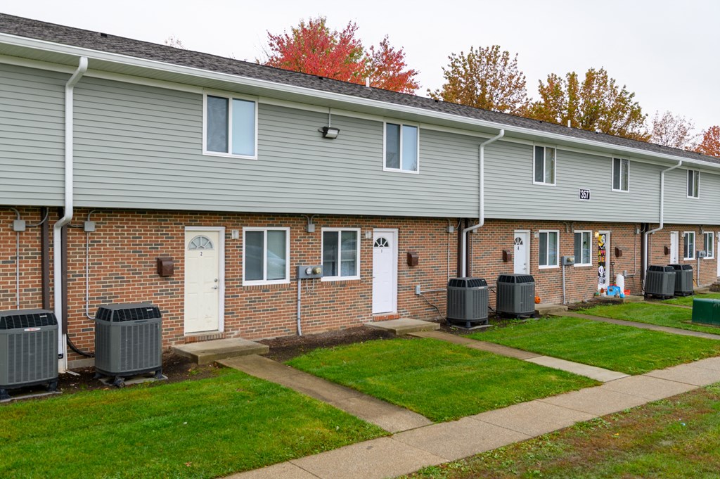 the front of a brick building with a sidewalk and grass