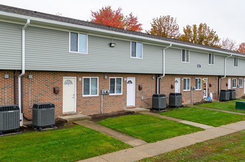 the front of a brick building with a sidewalk and grass