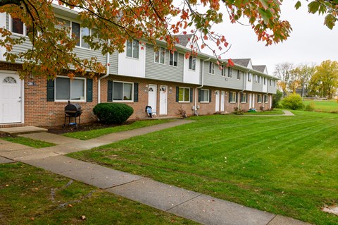 a row of houses with a green lawn and a sidewalk