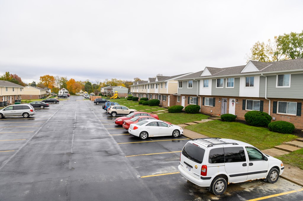 a parking lot filled with cars in front of houses