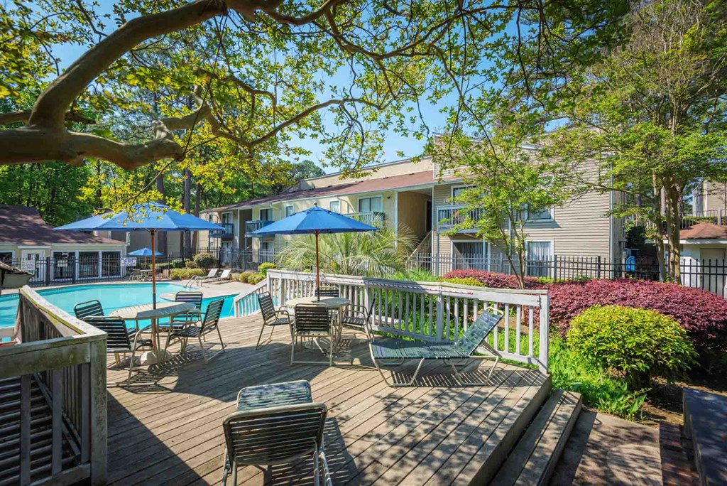 a patio with chairs and umbrellas and a swimming pool