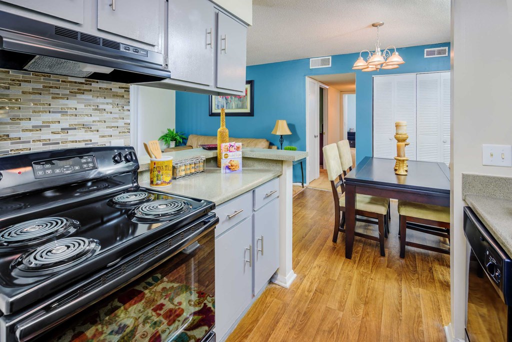 a kitchen with a stove and a dining room with a table