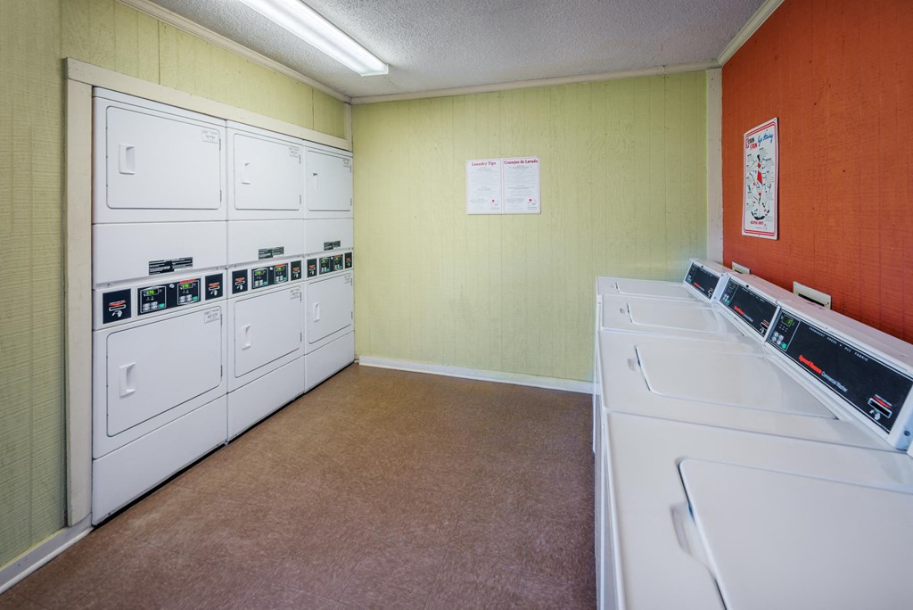 a laundry room with several washers and dryers and a wall of white appliances