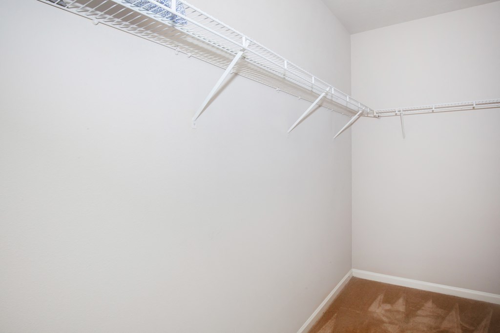 an empty closet with white walls and a window