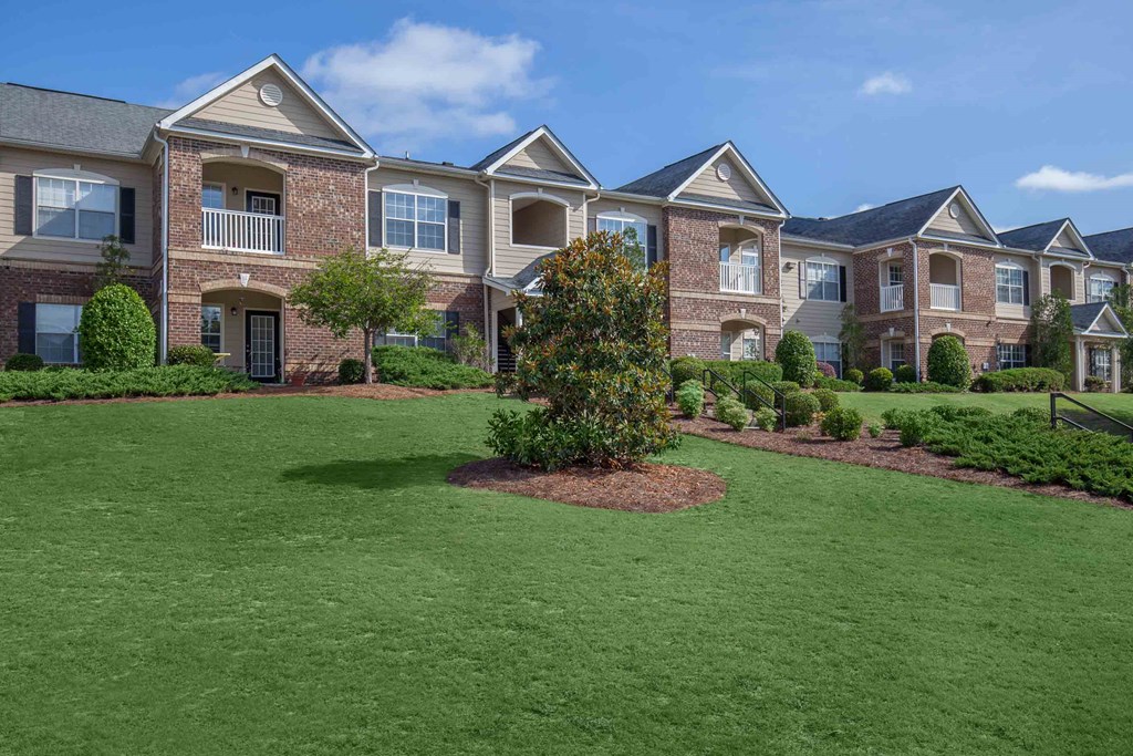 an image of an apartment building with green grass and shrubs