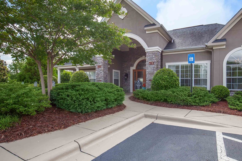 the front of a house with a driveway and trees and bushes