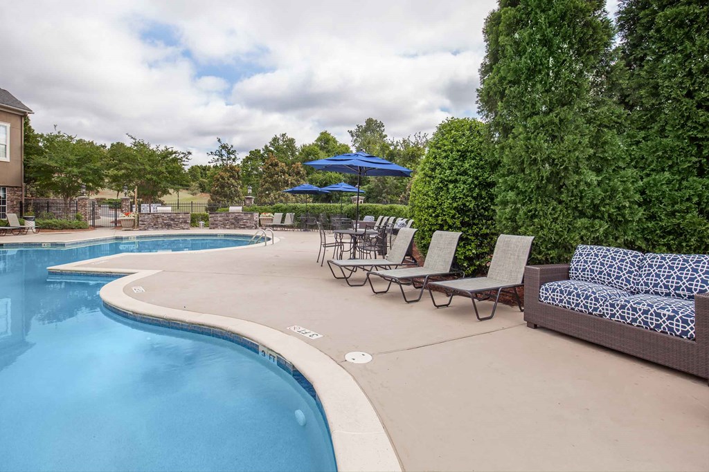 a swimming pool with lounge chairs and umbrellas next to a resort style pool