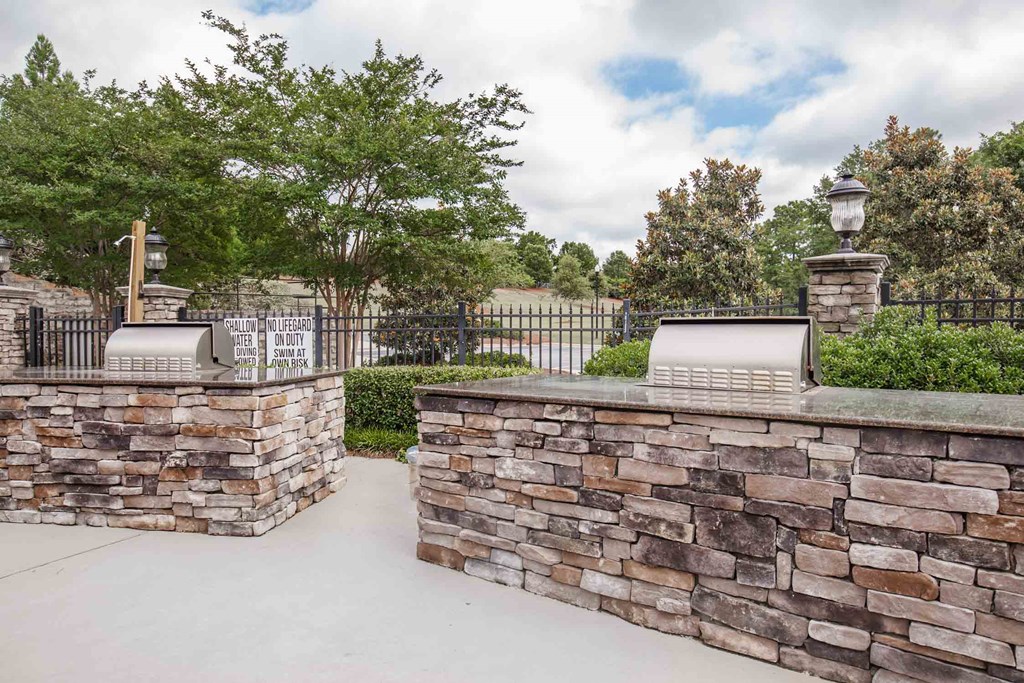 an outdoor entertaining area with a stone wall and a fence