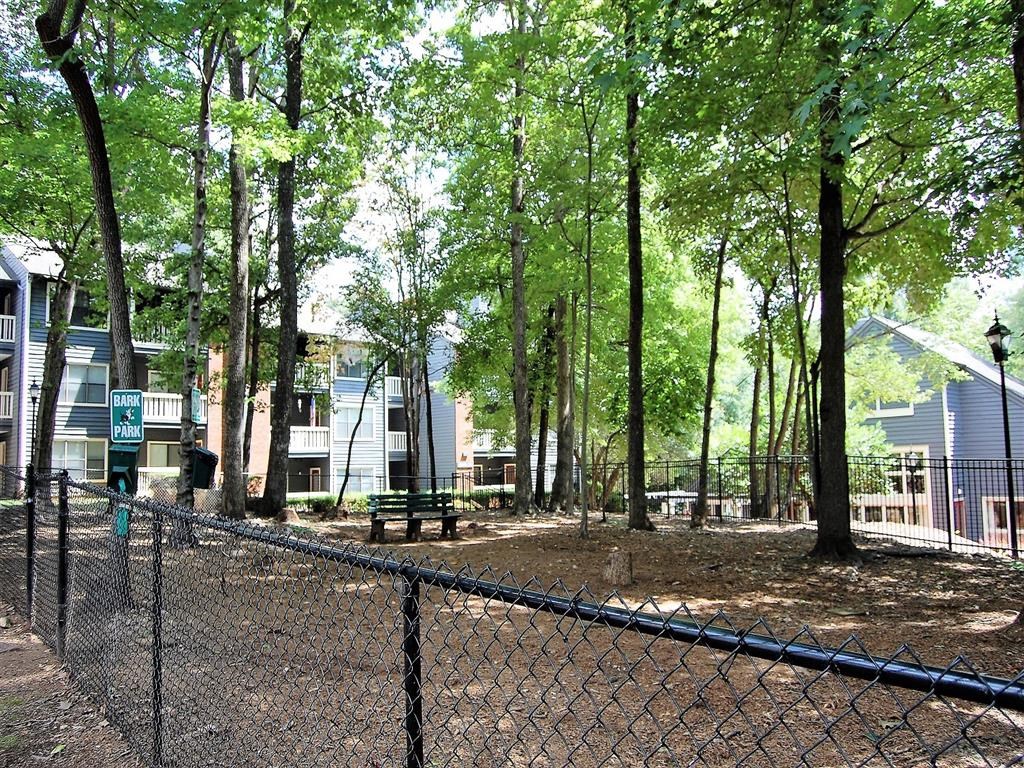 a fenced in park with trees and houses