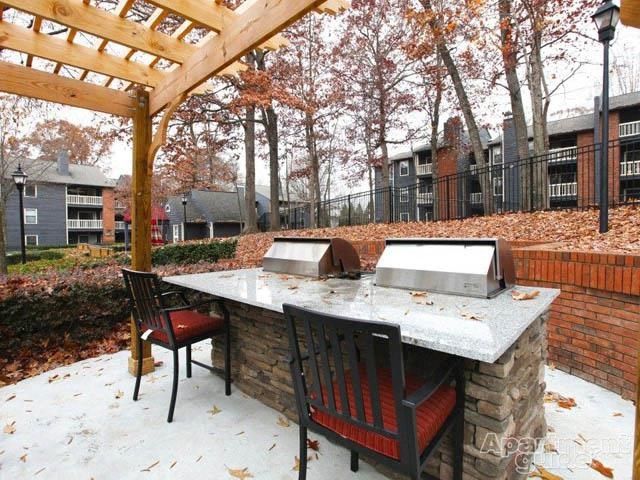 a patio with a grill and a table with chairs