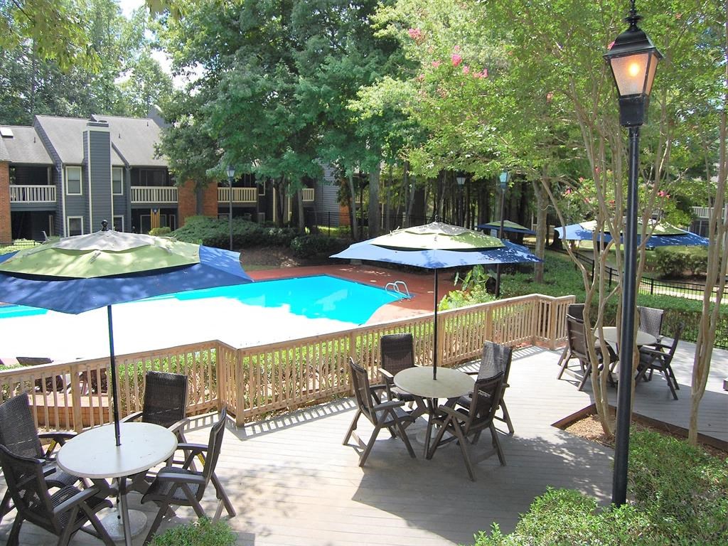 a patio with tables and umbrellas and a swimming pool