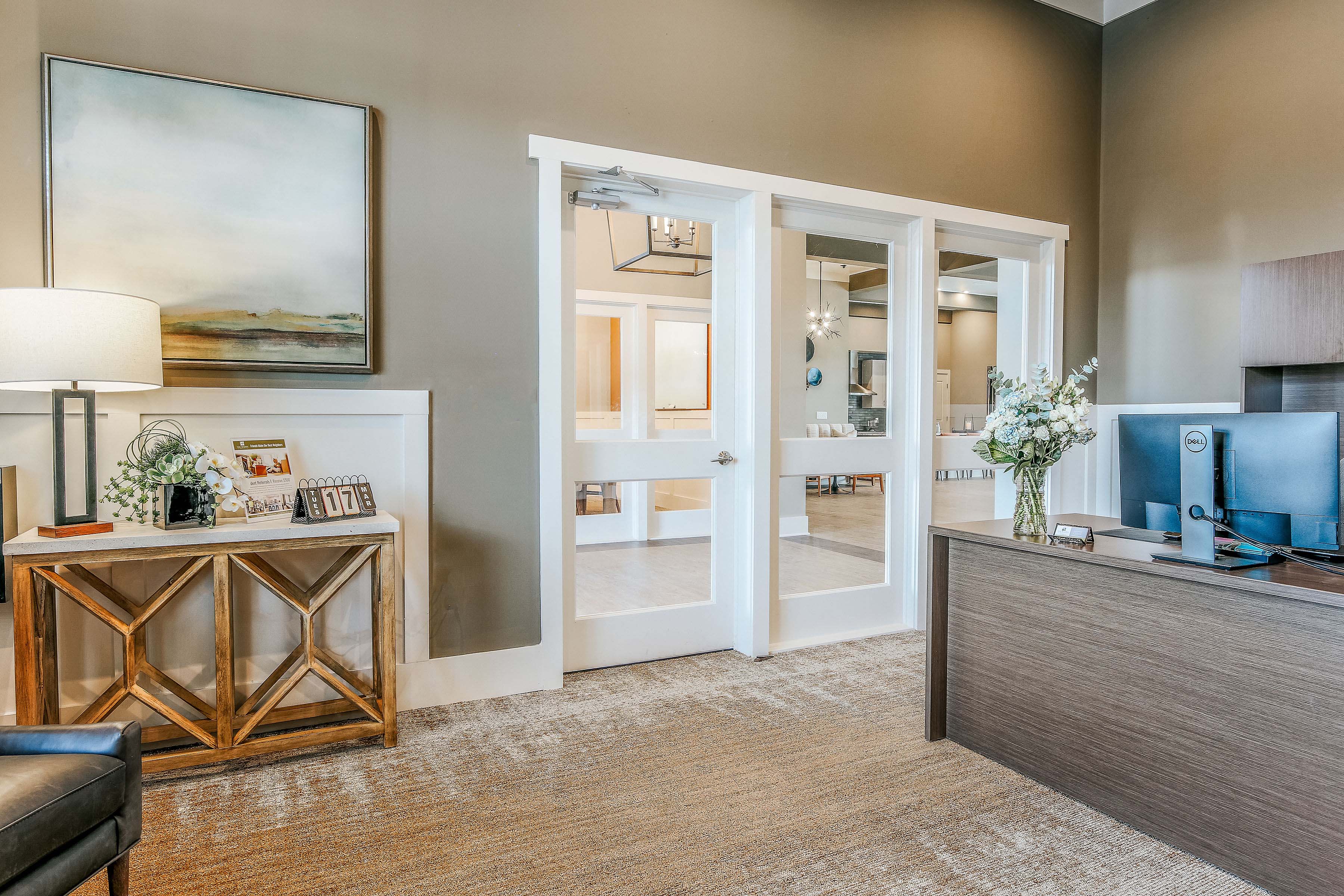 a living room with open doors to a bathroom and a desk