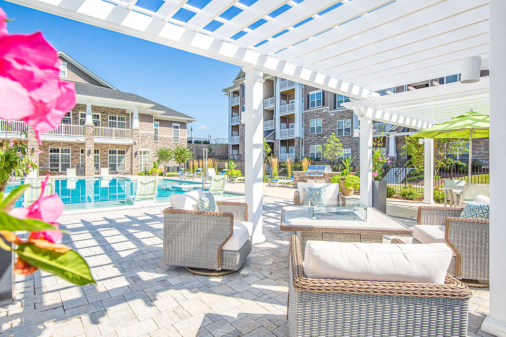 a patio with wicker tables and chairs and a pool