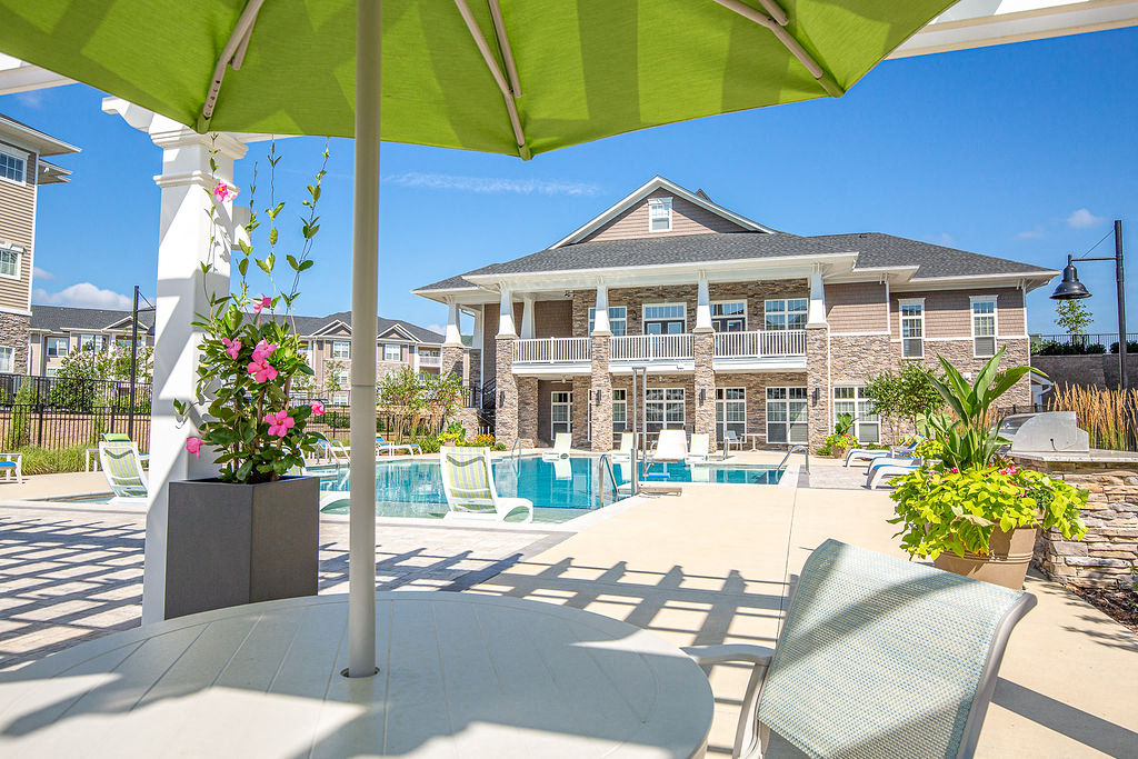 a large pool with chairs and an umbrella in front of a house