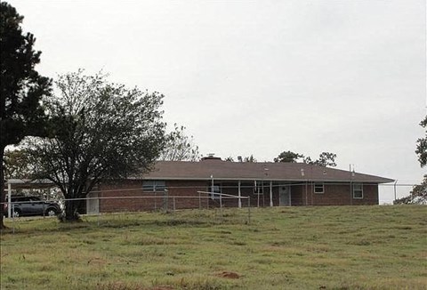 a brick house in a field with a fence