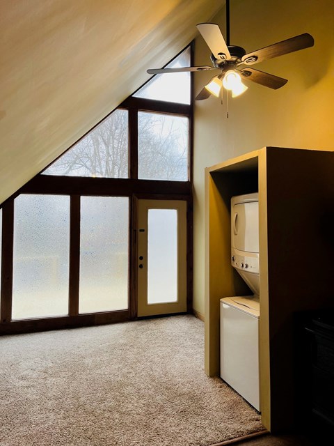 A room with a ceiling fan and a window with a view of trees.