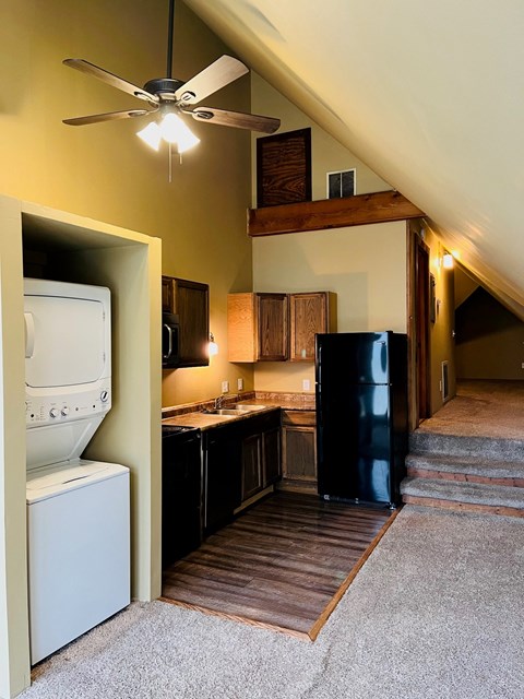 A kitchen with a white dishwasher and black refrigerator.