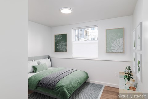 A bedroom with a bed, a window, and two framed pictures on the wall.