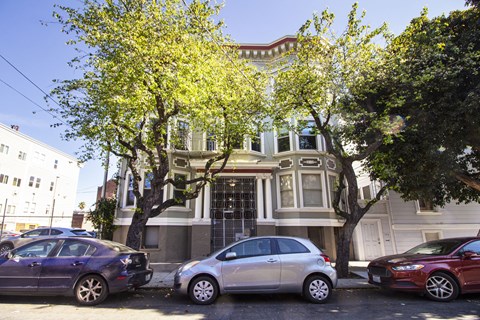 Three cars parked in front of a two-story building.