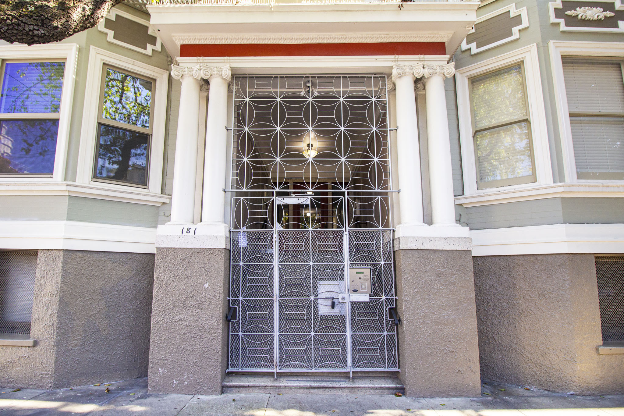 A white door with a metal grill is in front of a building.