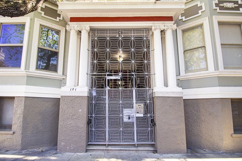 A white door with a metal grill is in front of a building.