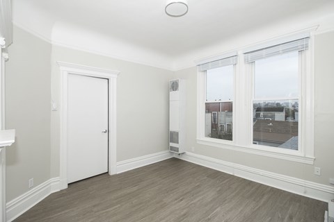 A room with a white door and a window with a view of a building.