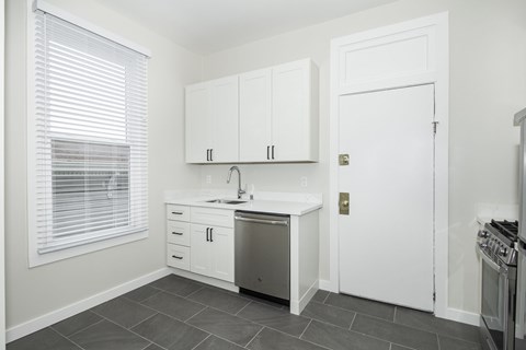 A kitchen with white cabinets and a stainless steel dishwasher.
