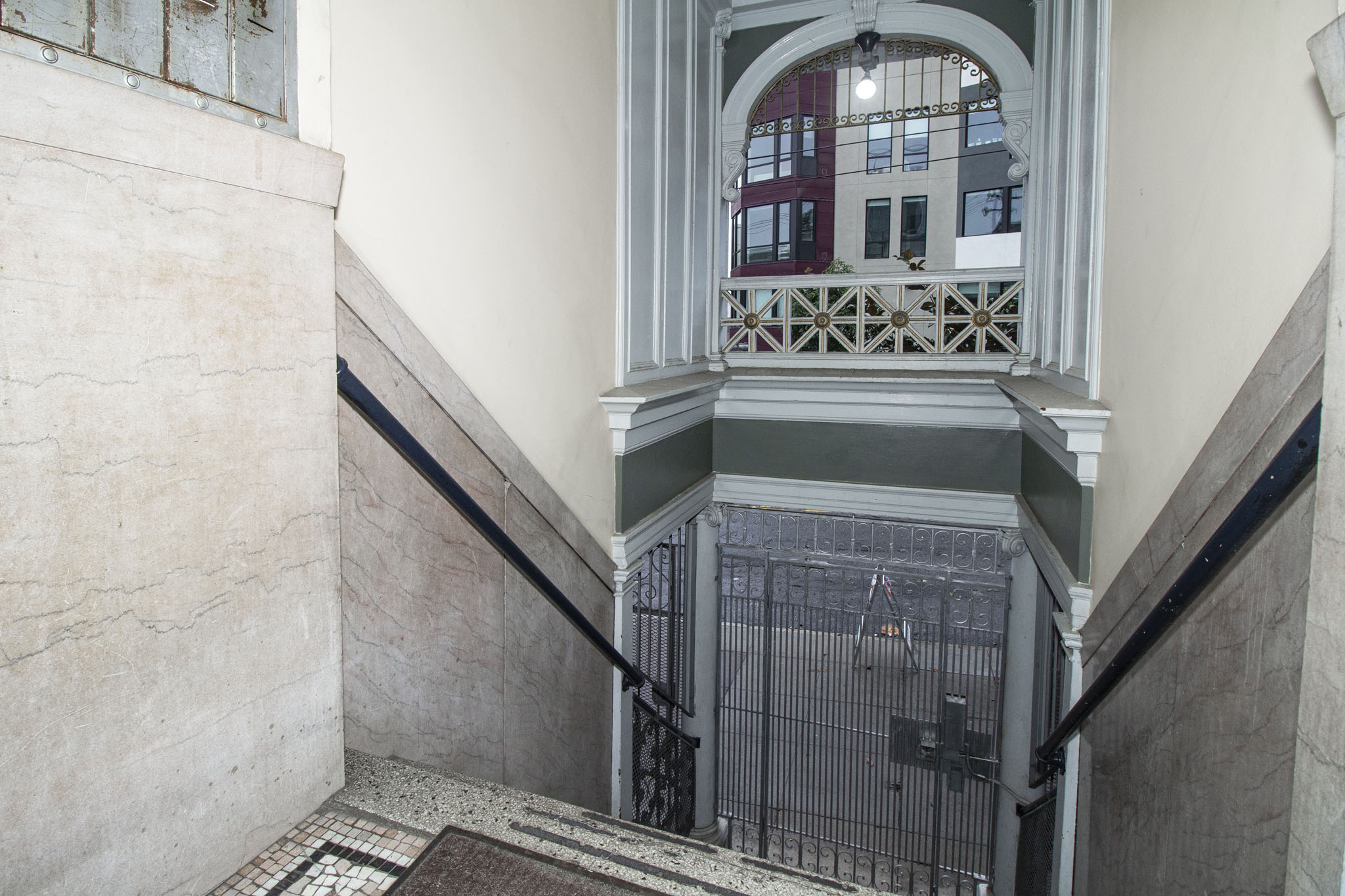 A staircase with a metal railing and a window with a view of a building in the background.