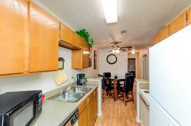 Kitchen with Hardwood-Style Flooring, Wood Cabinetry, White Appliances, and Double Sink