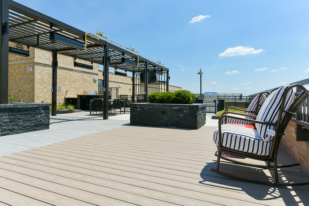 a deck with rocking chairs and a roof terrace with a building in the background