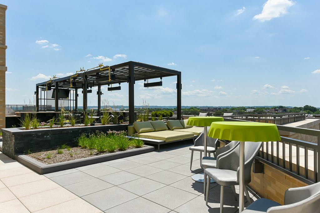 a roof terrace with couches tables and chairs and a pergola