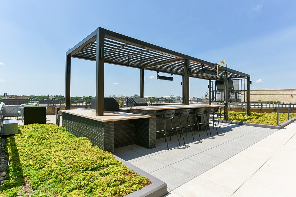 a patio with a bar and a pergola on a roof