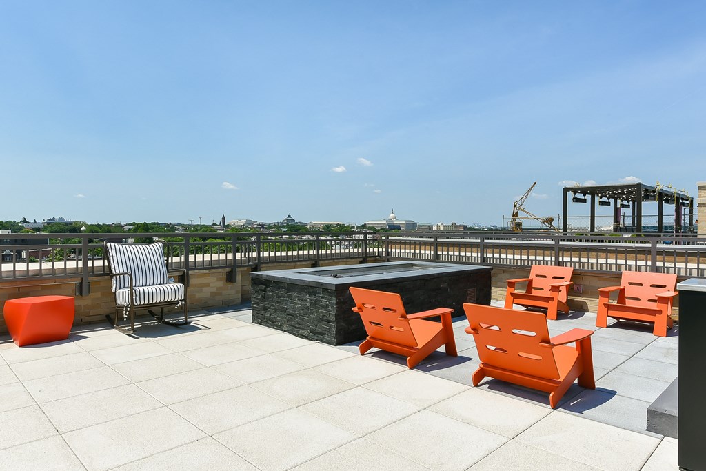 the rooftop terrace of the building has a fire pit and orange chairs