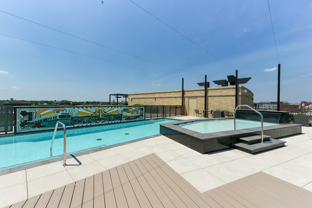 the pool on the rooftop of a building with a city in the background