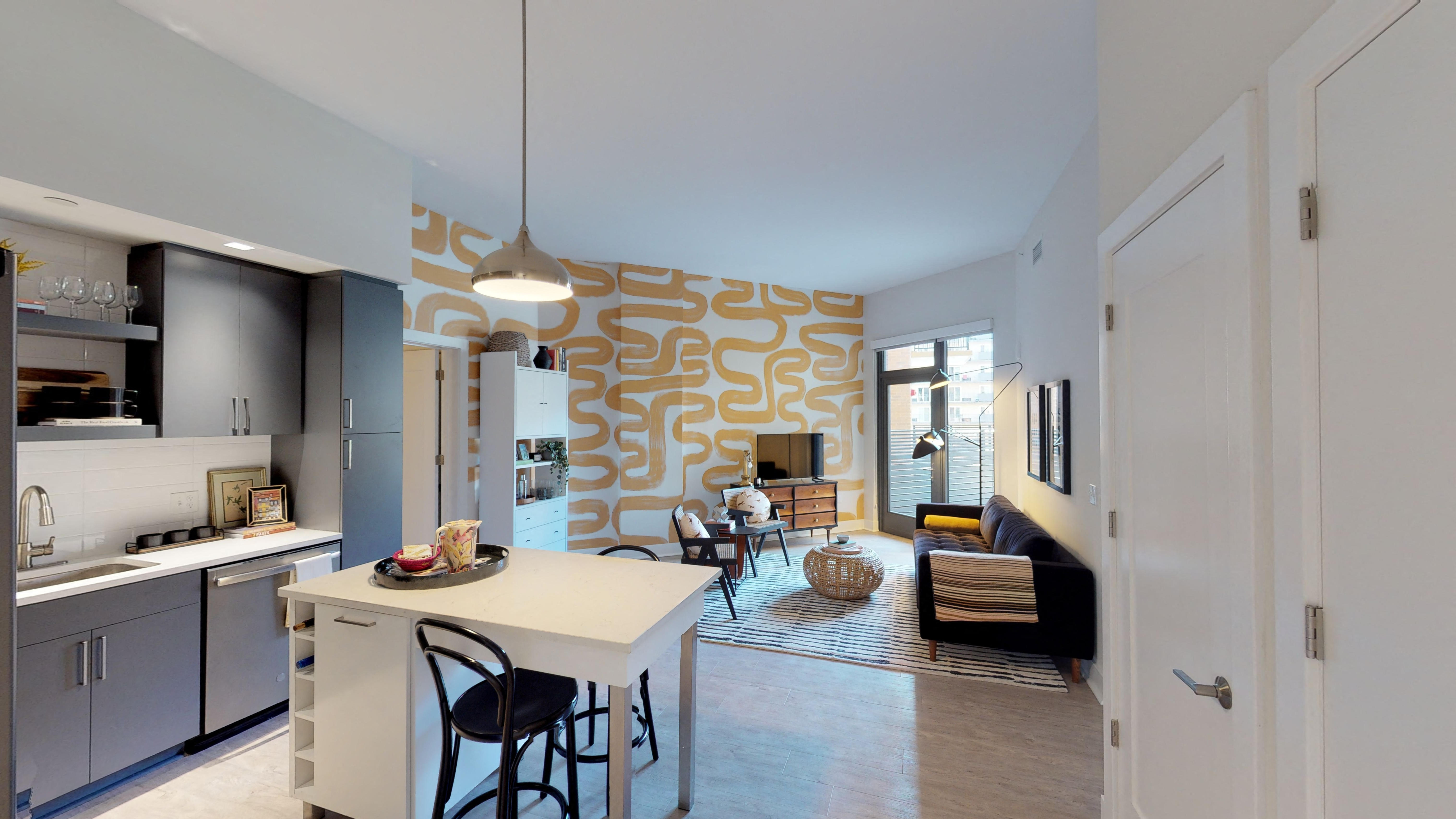 a kitchen with a white island and a living room with a fireplace