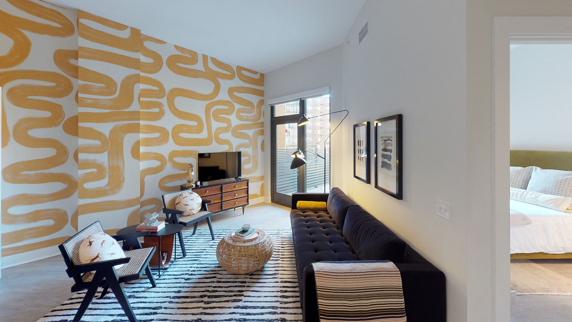 a living room with a yellow wall and a black couch