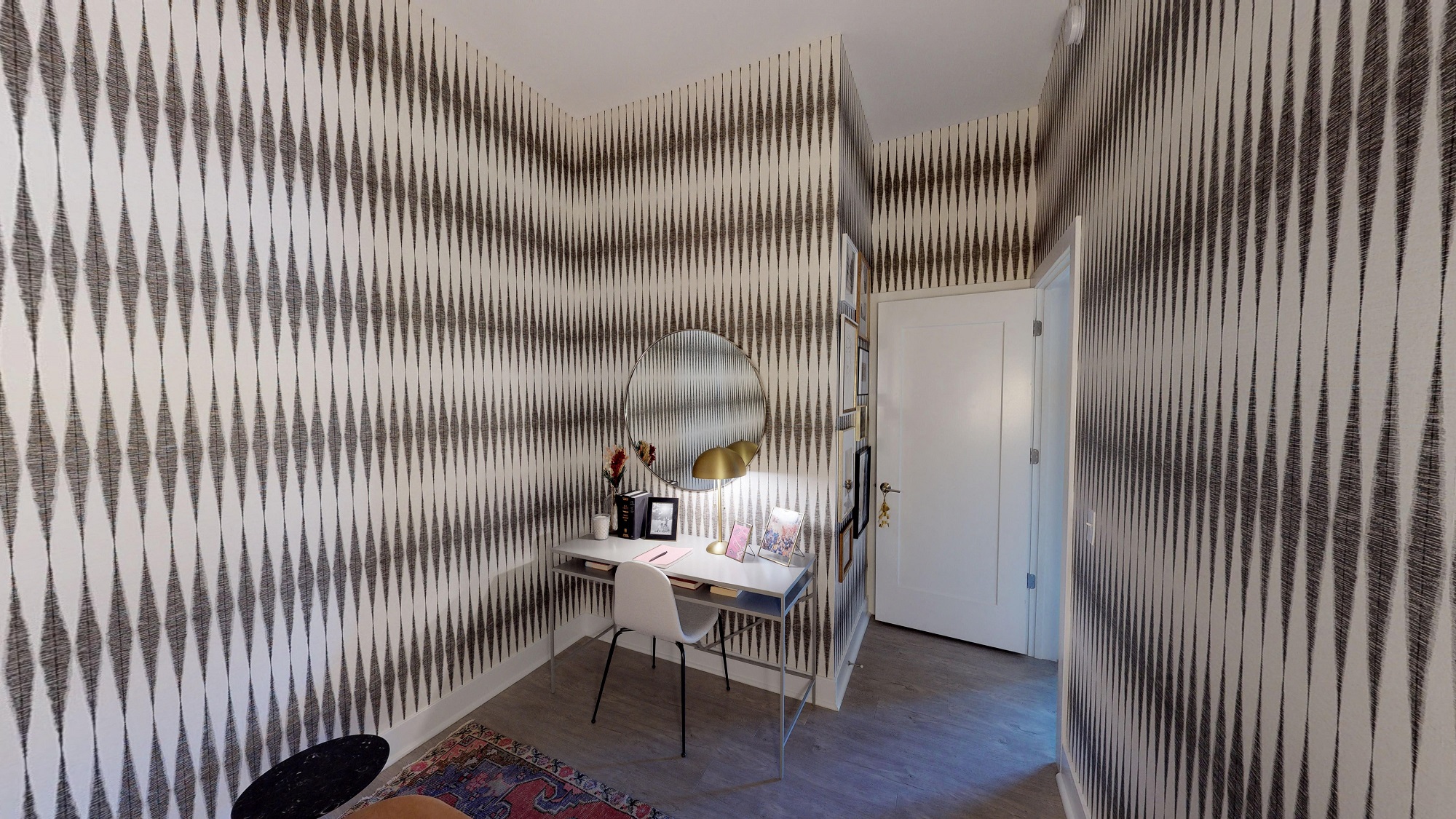 a small workspace with a desk and a mirror on the wall