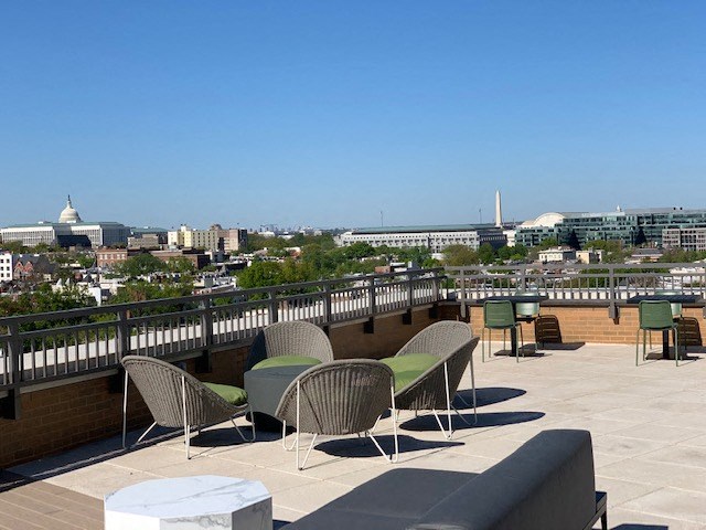 a rooftop patio with chairs and tables and a view of the city