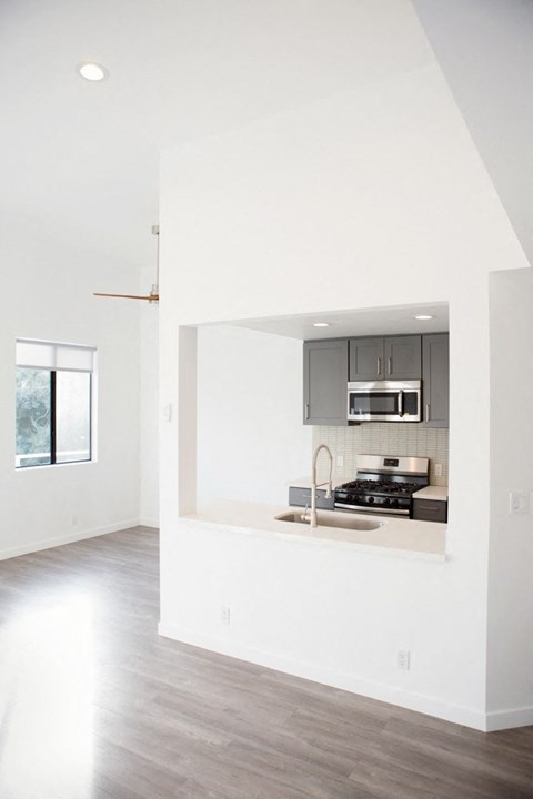 A kitchen with a stove, sink and cabinets.