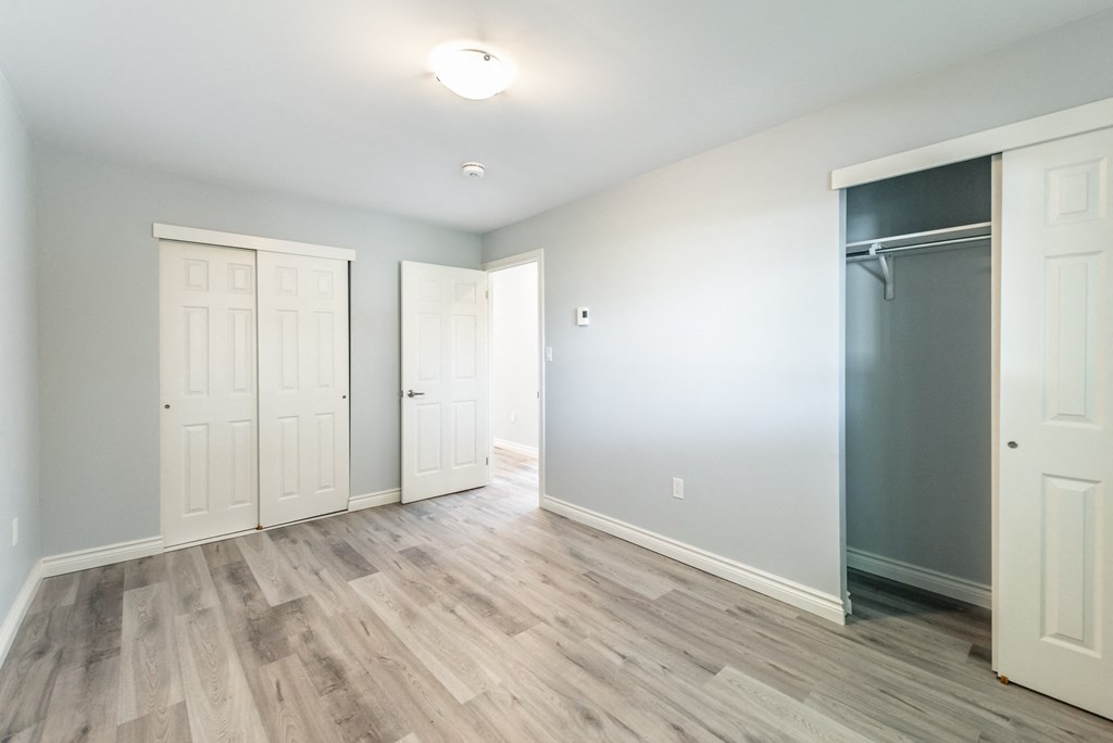 an empty room with white doors and a blue wall and a sliding closet