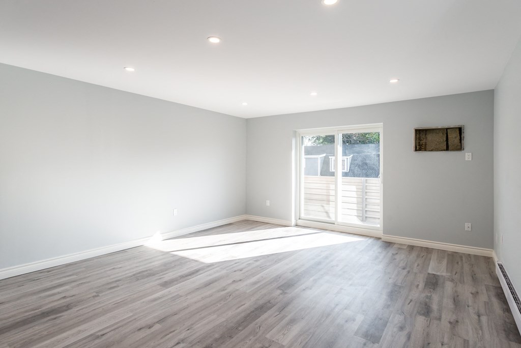 a living room with white walls and wood floors and a window