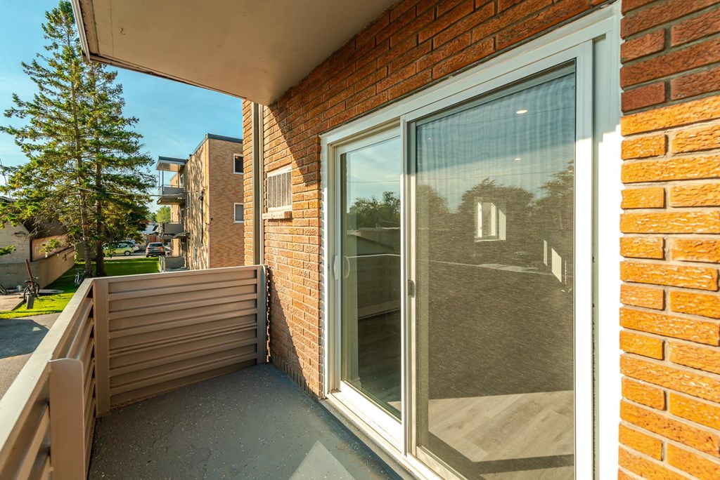 a balcony with a glass door and a brick wall