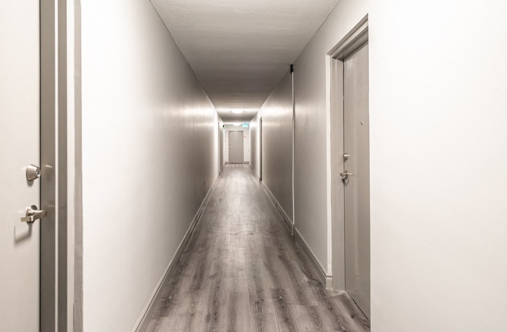 a long hallway with white walls and wooden floors and doors